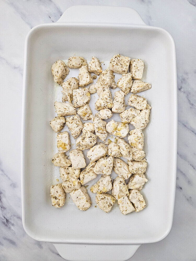 Biscuit pieces placed in a baking dish for biscuit pizza casserole.