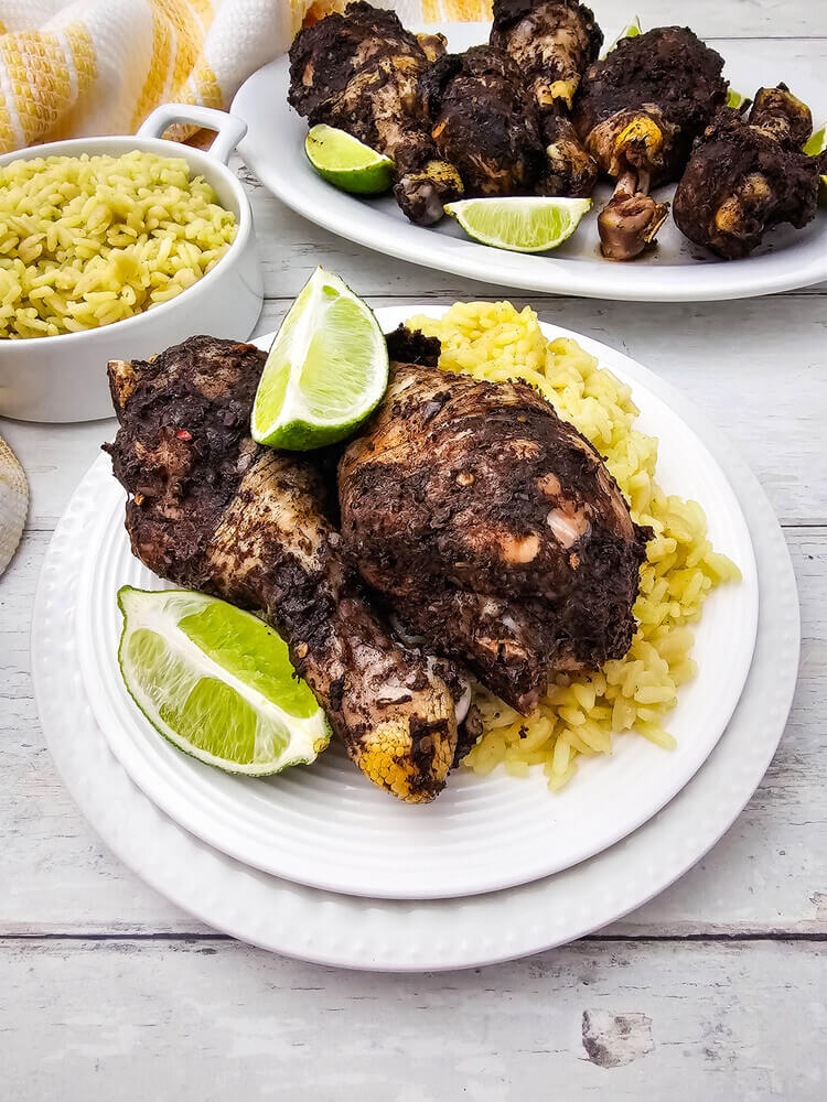 jerk chicken drumsticks recipe with lime wedges on a plate.