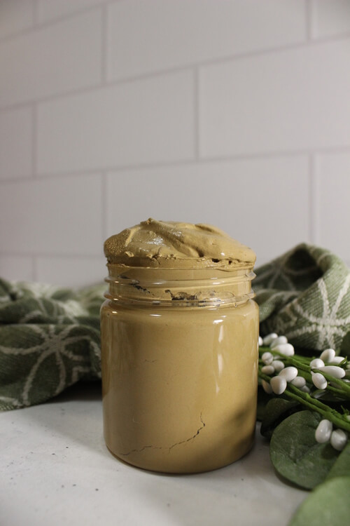 A jar of poison ivy paste diy beside a flower.